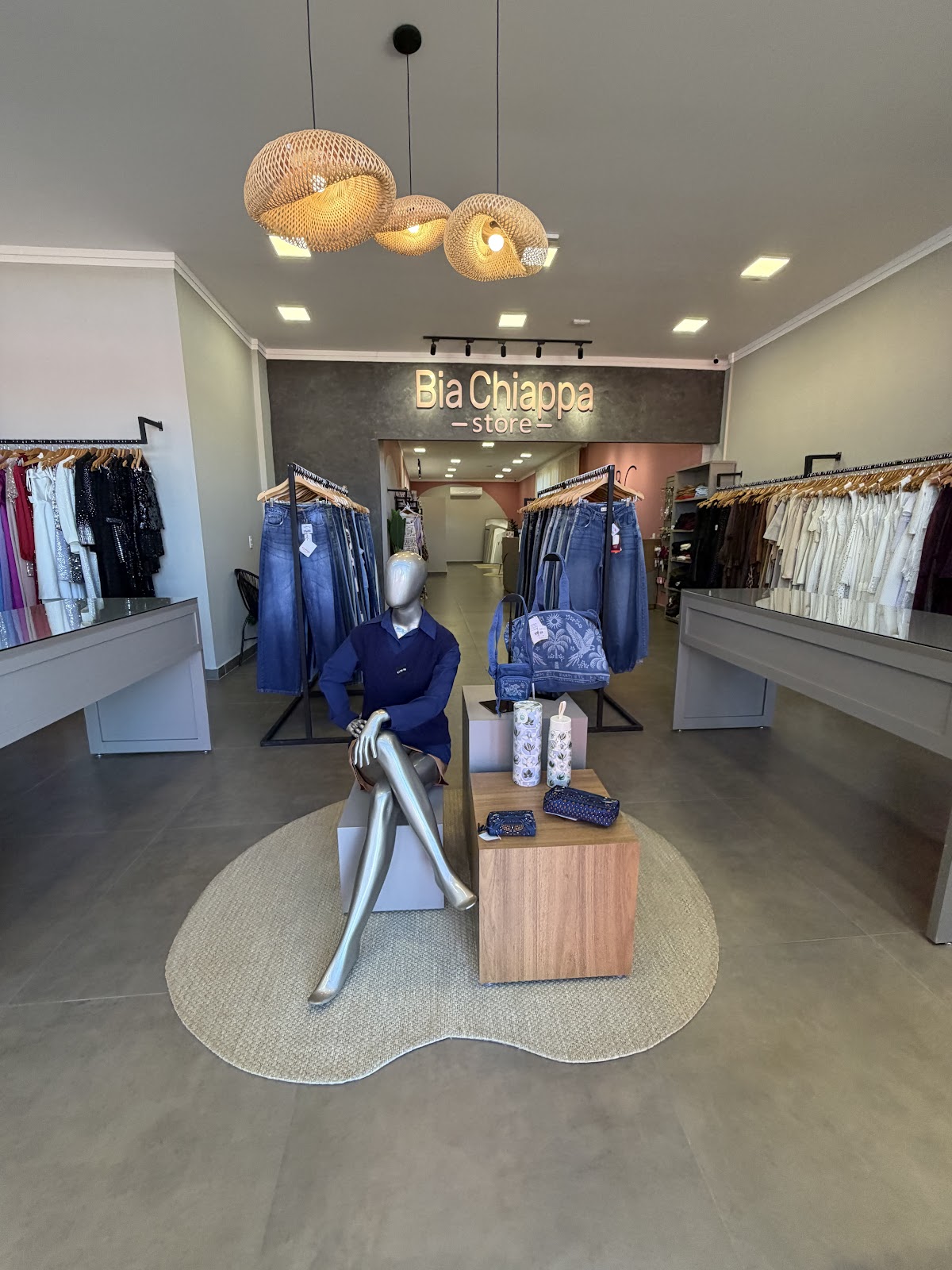 Interior da nova Bia Chiappa Store, com luminárias de palha, araras de roupas e tapete orgânico